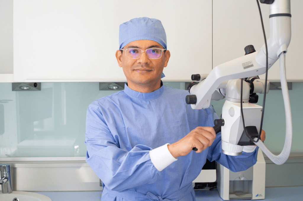 Zahnarzt in blauer OP-Kleidung mit Operationsmikroskop, spezialisiert auf Endodontie-Behandlungen